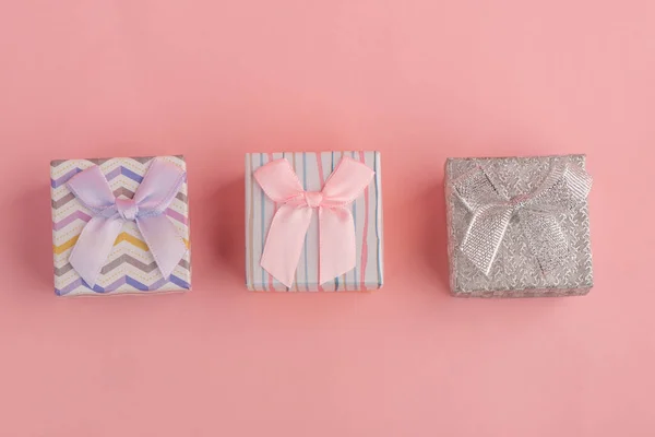 Три маленькі подарункові коробки на рожевому тлі, вид зверху — стокове фото