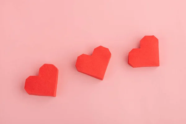 Tres corazones de papel rojo sobre fondo rosa —  Fotos de Stock