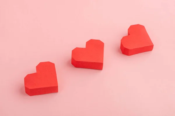 Tres corazones de papel rojo sobre fondo rosa —  Fotos de Stock