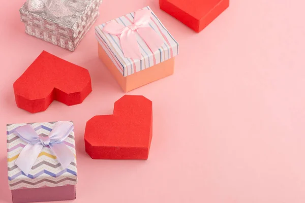 Pequeñas cajas de regalo y cajas de papel rojo sobre fondo rosa — Foto de Stock