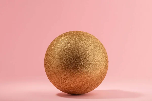 Bola de brilho dourado no fundo rosa claro — Fotografia de Stock