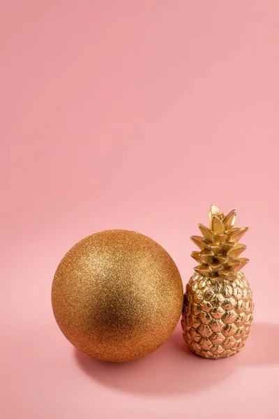 Золотий блискучий м'яч і пофарбований ананас на рожевому фоні — стокове фото