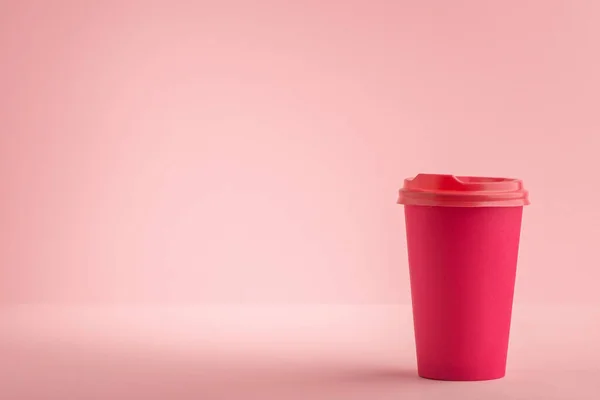 Copo de papel rosa com tampa de plástico no fundo rosa claro — Fotografia de Stock