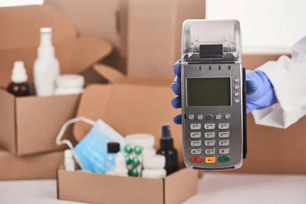 Close-up on a pharmacists hand holding a POS terminal