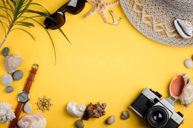 Deniz kabukları, aksesuarlar ve sarı arka planda kamera. Deniz kenarındaki maceralar