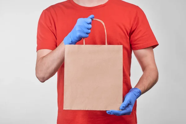 Mid-section portrait of a man delivering a paper bag with ordered food — Stock Photo, Image