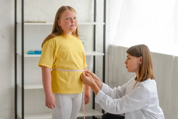 Médico que mide la cintura de las niñas, comprobar los resultados de una dieta — Foto de Stock