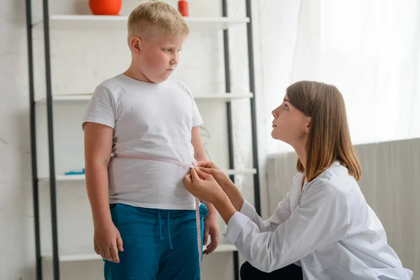 Kleiner pummeliger Junge wird von einem freundlichen Arzt gemessen — Stockfoto