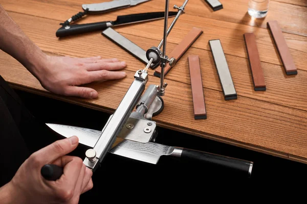 Man sharpening a Japanese knife with Damascus steel using a manual machine