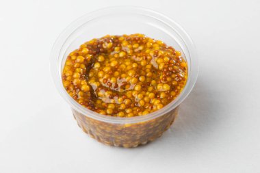 Beyaz arka planda tam tahıllı hardal bardağına yakın plan.