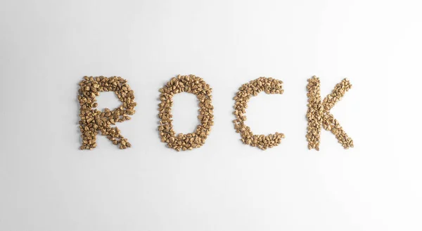 Вид зверху на позначення ROCK, зроблений із золотих самородків на білому тлі — стокове фото