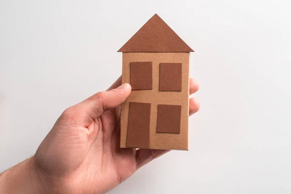 Primer plano en una mano sosteniendo una casa de papel sobre fondo blanco — Foto de Stock