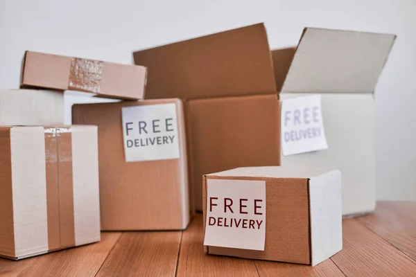 Various cardboard boxes with free delivery label on wooden table — Stock Photo, Image