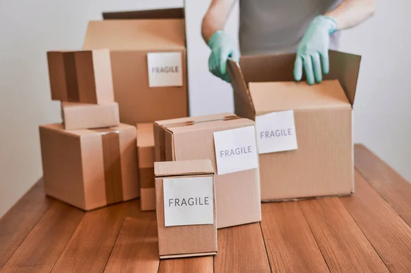 Man packing cardboard boxes with fragile labels — Stock Photo, Image