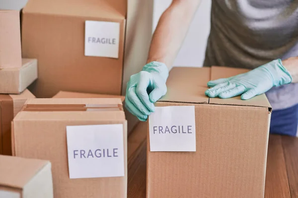 Postal worker putting a fragile label on a cardboard box — Stock Photo, Image