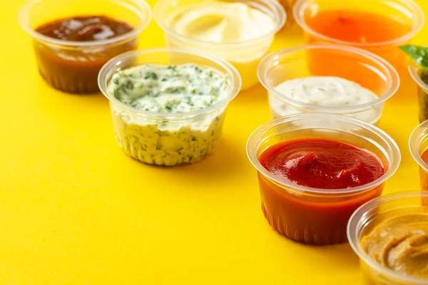 Nahaufnahme auf Tassen mit verschiedenen Saucen auf gelbem Hintergrund — Stockfoto
