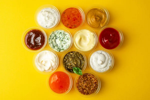 Draufsicht auf verschiedene Saucen in Tassen zum Eintauchen auf gelbem Hintergrund — Stockfoto