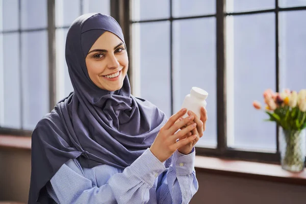 快乐的穆斯林女人，手里拿着一瓶药丸，面带微笑 — 图库照片