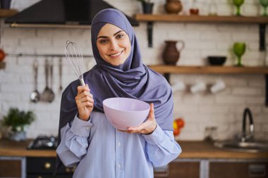 Zarif Müslüman kadın elinde kase ve bıyıkla poz veriyor.