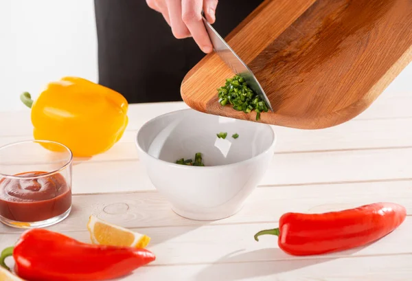 Hand taking cut green pepper off the wooden board with a knife — Stock Photo, Image