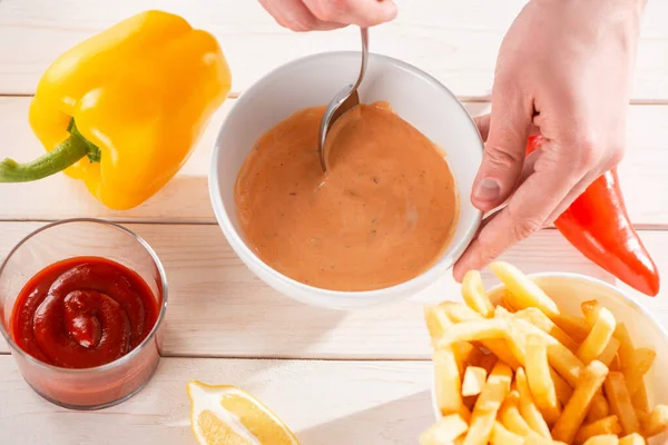 Vue de dessus sur une main mélangeant la sauce andalouse avec une cuillère — Photo