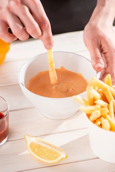 Gros plan sur une main trempant des frites dans une sauce andalouse — Photo