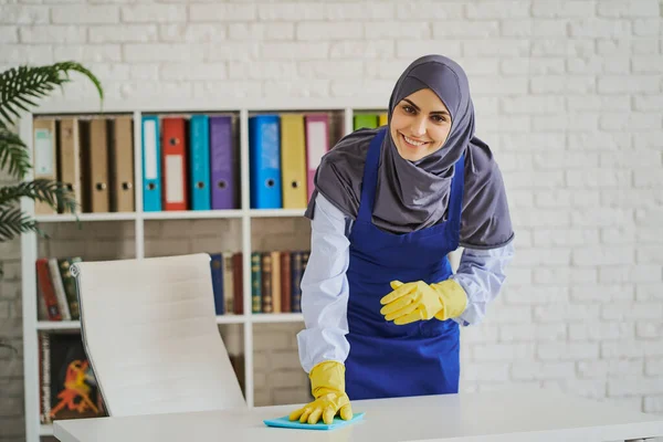 Mosolygó arab nő egy asztalt tisztít az irodában — Stock Fotó