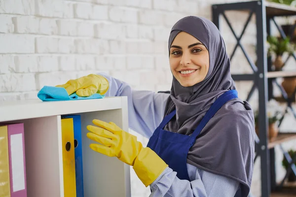 Portré egy gyönyörű muszlim nő takarítás polcok könyvekkel — Stock Fotó