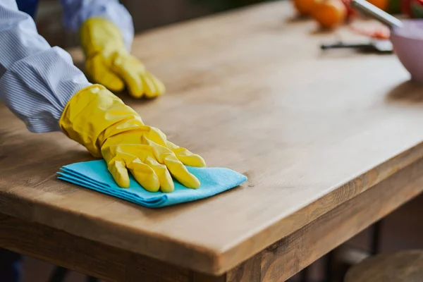 Close-up on a hand in glove cleaning a kitchen table with a rug — Stock Photo, Image