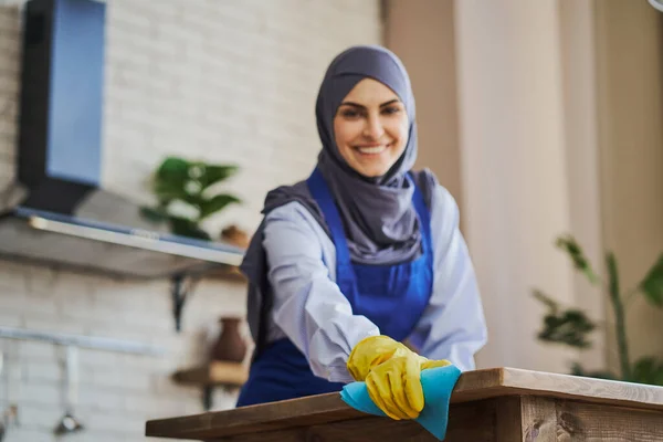 Muszlim nő visel kötényt és kesztyűt, miközben takarít a ház — Stock Fotó