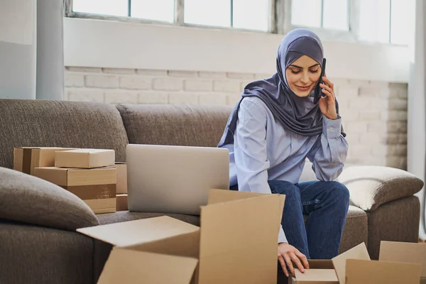 Arabische Geschäftsfrau telefoniert beim Verpacken von Bestellungen — Stockfoto
