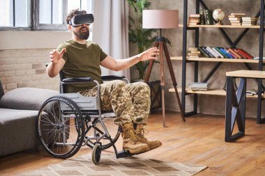 Tekerlekli sandalyede oturan ve VR kulaklık takan bir asker.