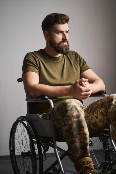 Saddened wojskowy siedzi na wózku inwalidzkim w szpitalu i myśli Obrazy Stockowe bez tantiem