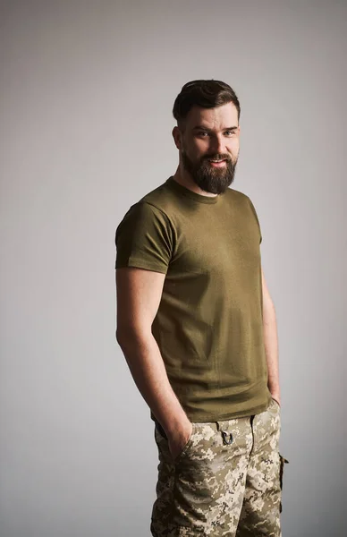 Porträtt av en glad serviceman i en militär uniform på grå bakgrund — Stockfoto