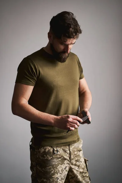 Strong military man sharpening his pocket knife with a whetstone Stock Image