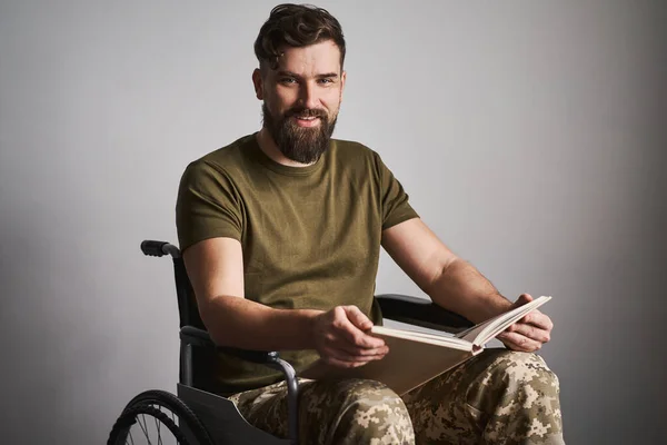 Happy military man sitting in a wheelchair and watching album photos Stock Photo