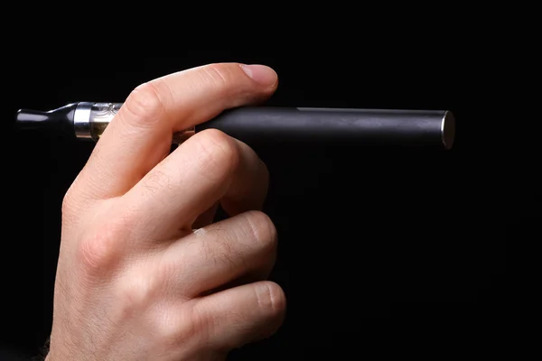 Mão segurando cigarro eletrônico em um fundo preto — Fotografia de Stock