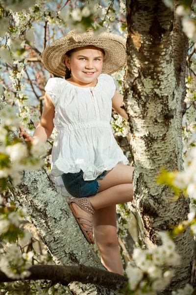 Linda niña jugando en el árbol a principios de primavera — Foto de Stock