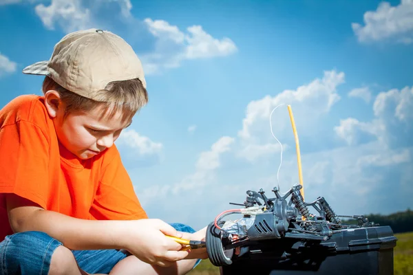 Мальчик ремонтирует радиоуправляемую машину на открытом воздухе возле поля. — стоковое фото