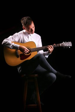 Siyah arka planda gitar çalan genç adamlar