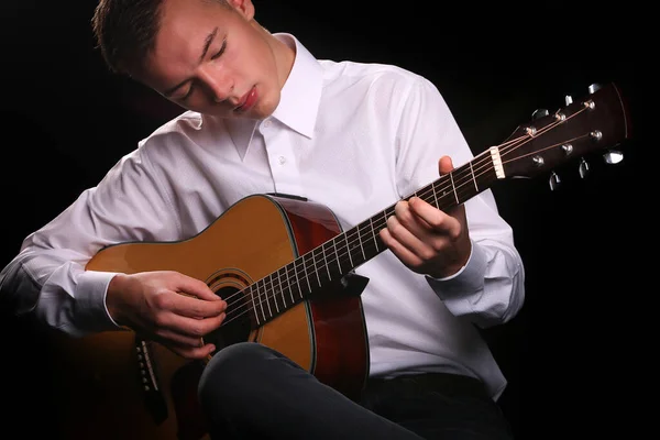 Young men playing the guitar with black background