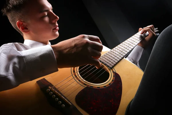 Young men playing the guitar with black background