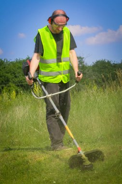 Çim biçme makinesiyle çim biçen işçiler