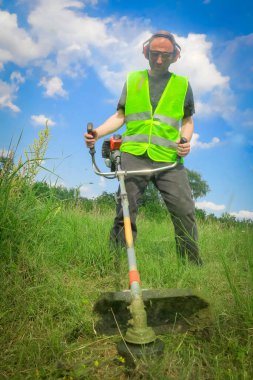 Çim biçme makinesiyle çim biçen işçiler