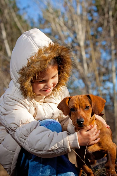 Lykkelig liten pike som leker med en stor hund i skogen om høsten – stockfoto