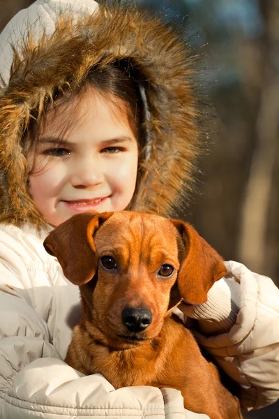 Fröhliches kleines Mädchen spielt im Herbst mit großem Hund im Wald — Stockfoto