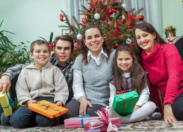 Family exchanging gifts in front of Christmas tree — Stock Photo, Image