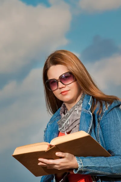 Молодая женщина стоит летом, зеленый парк чтение книги — стоковое фото