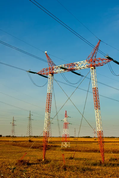 Yüksek gerilim enerji iletim hatları ve pilonlar silueti bir — Stok fotoğraf