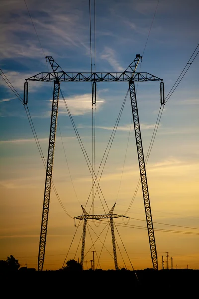 Yüksek gerilim enerji iletim hatları ve pilonlar silueti bir — Stok fotoğraf